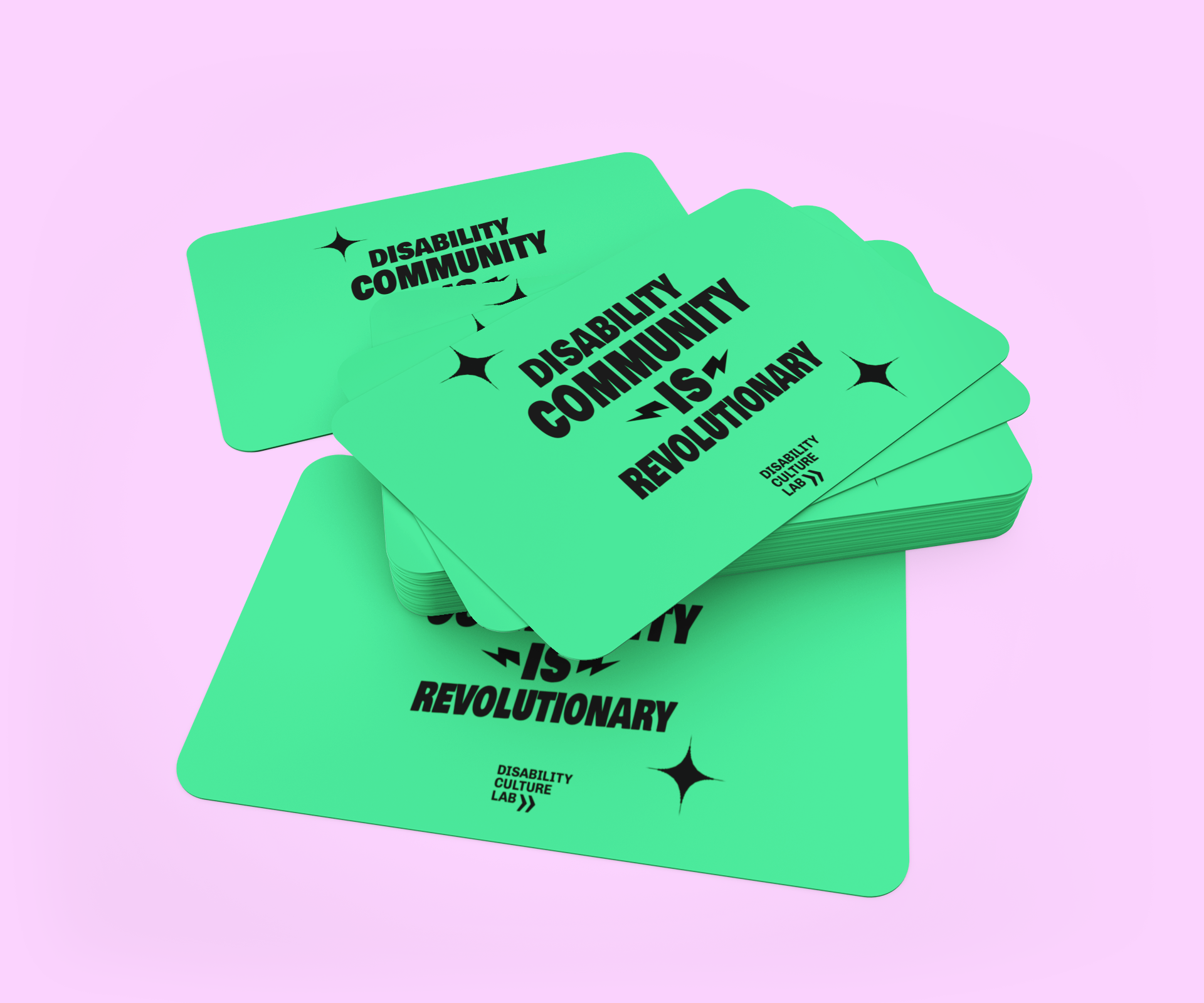 Piles of green Disability Culture Lab Gift Cards featuring black text that says "Disability Community is Revolutionary" on a pink background. Stars embellish the corners, with "Disability Culture Lab Store" printed at the bottom.