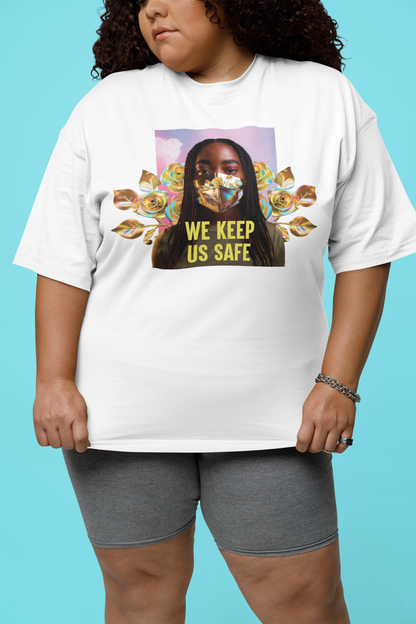 A person wears the "We Keep Us Safe Tee" from Disability Culture Lab, which is Union Printed and Made in the USA. Designed by Jennifer White-Johnson, this white T-shirt displays a graphic of a masked portrait surrounded by flowers, accompanied by the words "WE KEEP US SAFE." The individual pairs it with gray shorts against a light blue background.