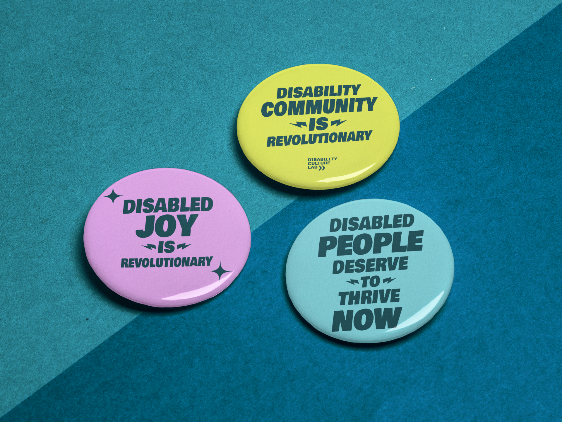 Introducing the Limited Edition Button 3 Pack from Disability Culture Lab: a set of three pinback buttons featuring empowering messages on a striking two-toned blue background. The designs include: Pink - "Disabled joy is revolutionary," Yellow - "Disability community is revolutionary," and Blue - "Disabled people deserve to thrive now." These inspiring buttons, created by a disabled artist, are proudly union printed.